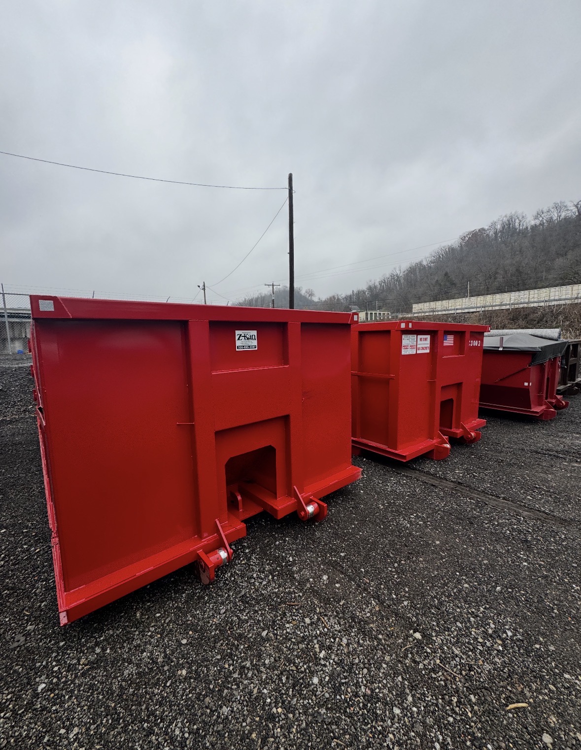 Fleet of freshly painted red Pascarella roll-off dumpsters staged at the yard