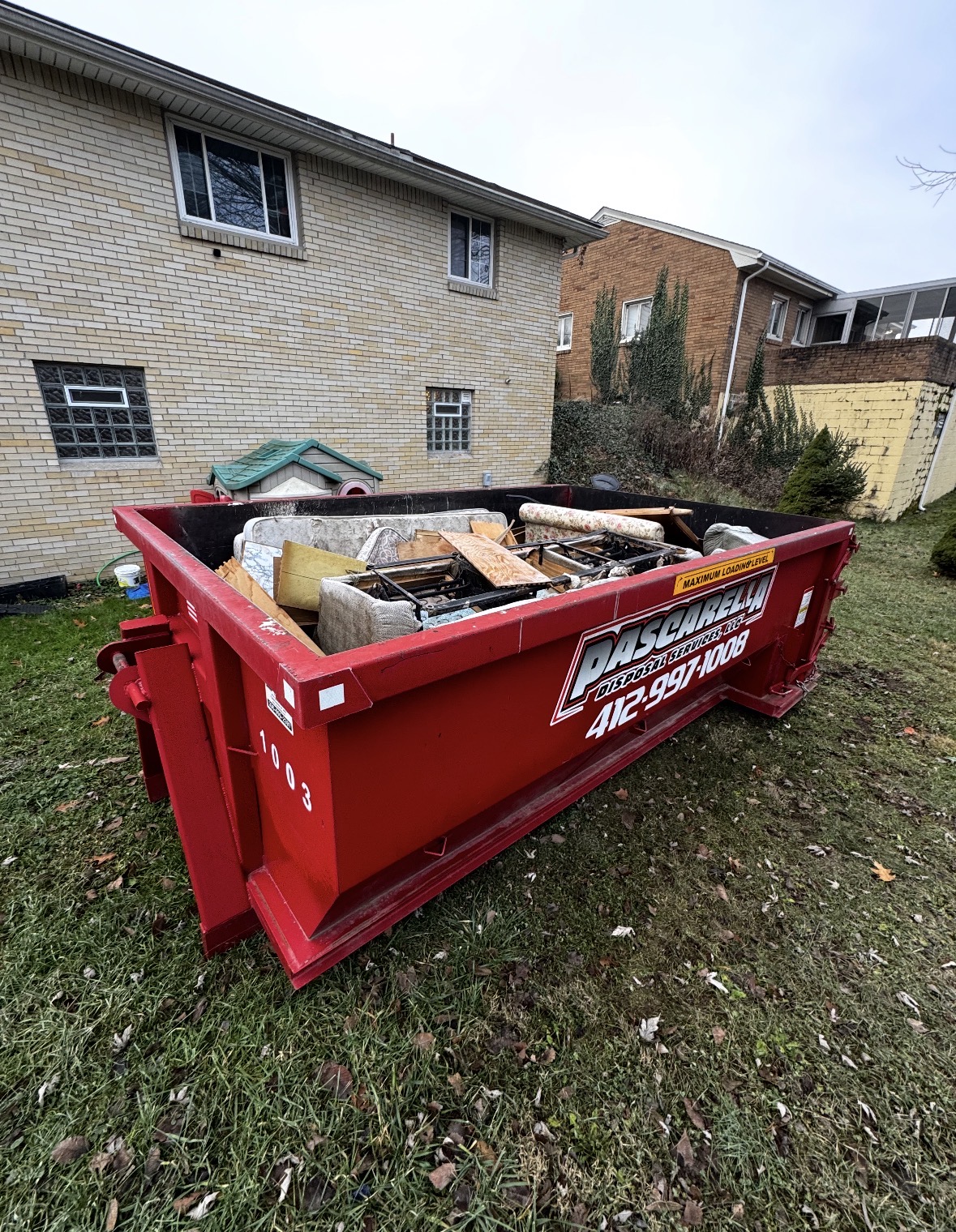 Family loading household items into a residential dumpster