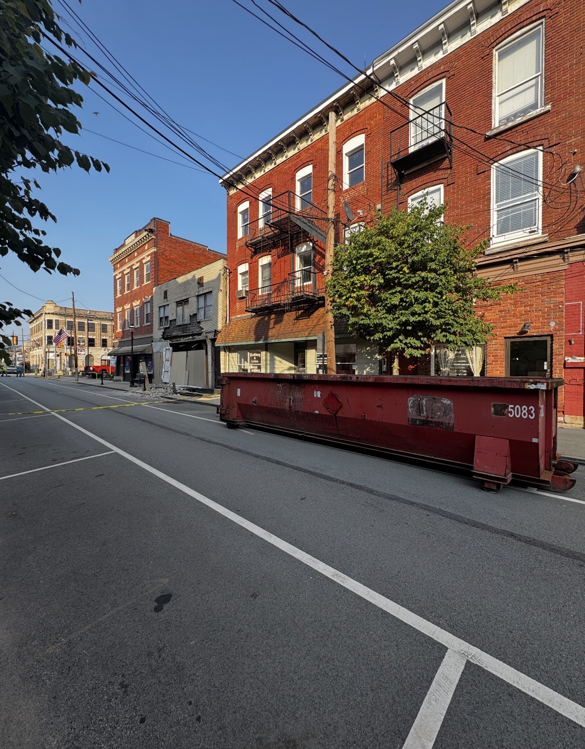 Pascarella red roll-off dumpster on a downtown Monongahela street next to brick buildings