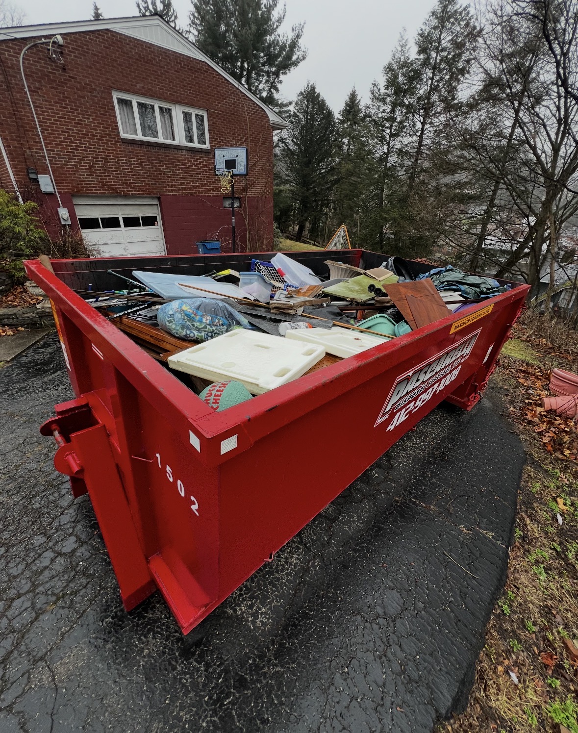 Full Pascarella dumpster on a steep residential driveway after a home cleanout