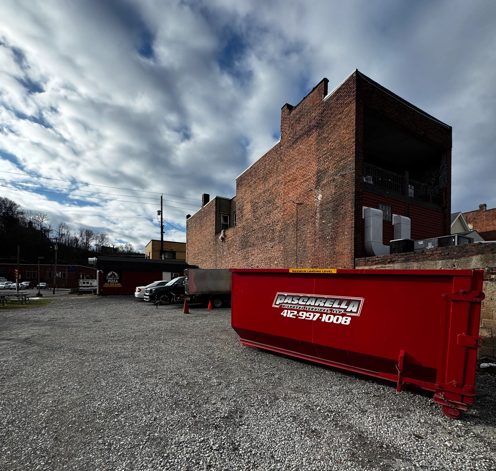 Pascarella red roll-off dumpster staged in a downtown Monongahela lot