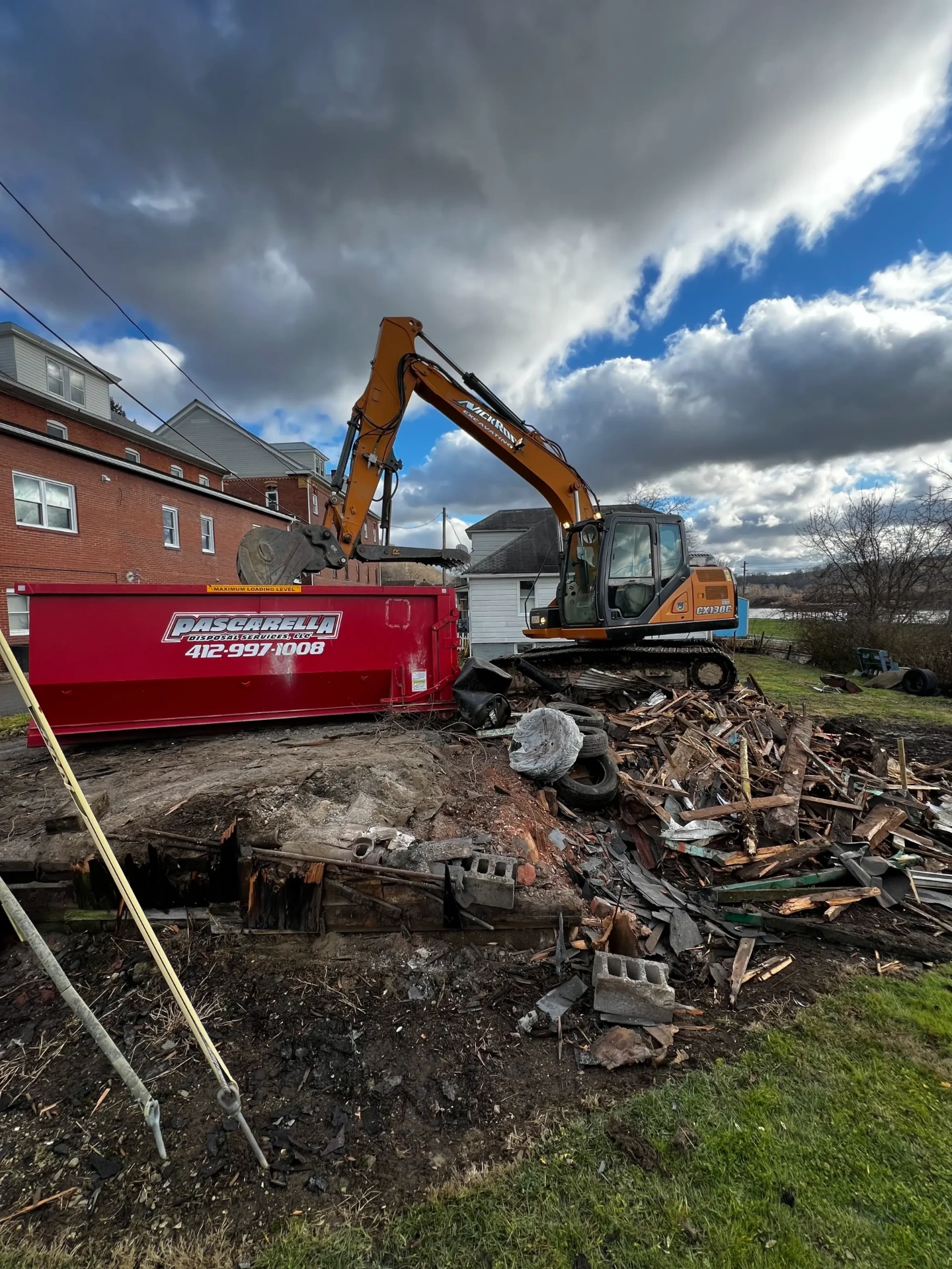 Excavator loading demolition debris into a Pascarella dumpster