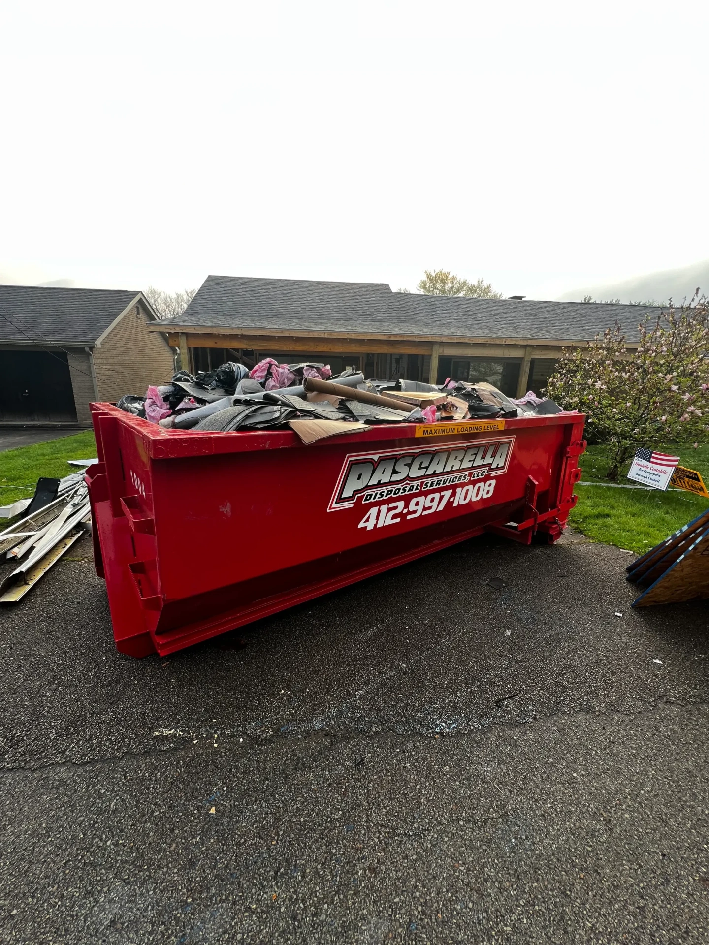 Full Pascarella dumpster after a roofing tear-off on a residential driveway